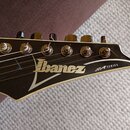 Fotografie zachycuje hlavu elektrické kytary v černé barvě s bílým lemováním. Na povrchu je bílé logo Ibanez a nápis SA SERIES. Jsou vidět šest kovov…