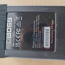 Detail spodní strany černého efekt pedálu s nalepeným velkro páskem. Na černém štítku je bílé logo BOSS a nápisy: CAN ICES-003(B)/NMB-003(B), UK CA C…