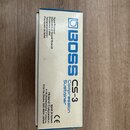 Fotografie znázorňuje papírovou krabici od efekt pedálu. Na modrém panelu je uveden bílý nápis BOSS CS-3 Compression Sustainer. Na bílém boku krabice…