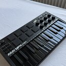 Černý kompaktní MIDI kontrolér s klávesnicí a padovými polštáři. Na přístroji je bílý nápis AKAI PROFESSIONAL MPK mini. Povrch je v dobrém stavu, bez…