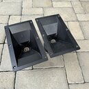 Dvě černé plastové akustické membrány (trumpety) s obdélníkovým základním profilem. Povrch je matně černý a vykazuje drobné nečistoty a prach. Na pře…