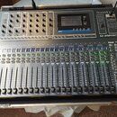 Šedý mixovací pult s názvy Soundcraft a Si IMPACT. Zařízení obsahuje digitální displej, zahlreiche posuvníky, tlačítka a otočné ovladače. V pravé hor…