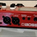 Červený vokalní procesor značky BOSS, model VE-22. Na zadním panelu jsou vstupy a výstupy s popisky INPUT MIC, OUTPUT R a L/MONO, PHONES/LINE OUT, AU…