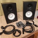Dva černé studiové monitory s bílými membránami basových reproduktorů a černými výškami. Na spodní části obou reproduktorů je bílé logo Yamaha. K nim…