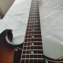 Elektrická kytara s tmavě hnědým sunburst povrchem těla a hnědým hmatníkem. Tělo má tmavě červený želvový pickguard a bílý snímač. Na hranách těla js…