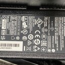 Fotografie znázorňuje černý plastový síťový adaptér s textem a certifikačními logy. Na štítku je uveden výrobce DELTA ELECTRONICS, INC. a model ADP-0…