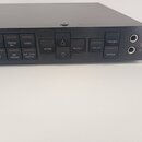 Černý rackový procesor s řadou ovládacích tlačítek. Na panelu jsou nápisy SCROLL BACK, PARAM, LEVEL, EQ, INT PARAM, EXT CTRL ASSIGN, STORE, RECALL, U…