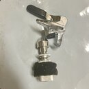 Fotografie zobrazuje dvě chromované kovové součástky, pravděpodobně části mechanismu pro ladění nebo upevnění nástroje. Horní díl obsahuje černou pla…