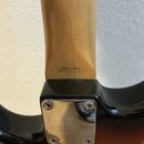 Detail zadní strany krku a spoje s tělem kytary. Na dřevěném krku je černý nápis „Crafted in Japan“ a pod ním „s/n A033196“. Spoj s tělem je zakrytý…