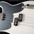 Detail bílé elektrické basové kytary s černým pickguardem. Na snímačích je viditelný nápis seymour duncan. Povrch nástroje a plastové části jsou v či…