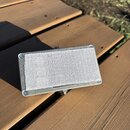 Kovový efekt pedál stříbrné barvy s bílým plátěným povrchem ve středové části. Na levé straně je svisle napsaný nečitelný text. Zařízení je přišroubo…