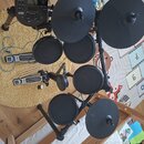 Elektronická bicí souprava značky Alesis s černými pady a činely. Na modulu je vidět nápis Alesis a model Nitro Mesh Kit. Souprava obsahuje pět padů,…