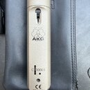Detail zlatavého mikrofonu s nápisem AKG pod logem tří propletených kruhů. Pod logem je uveden model C 1000 S, značka CE a nápis MADE IN POLAND. V ho…