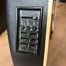 Detailní pohled na černý plastový předzesilovač s ekvalizérem zabudovaný v těle nástroje. Na panelu jsou vidět posuvníky s popisky Volume, Bass, Mid…