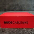Červená papírová krabice s černým nápisem RØDECABLE(6M). Povrch krabice vykazuje mírné pomačkání a opotřebení v horní části.