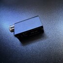 Černý obdélníkový modul s kovovým konektorem na jedné straně. Na horní části je bílý nápis Automatic Microphoneswitch a označení PB-05. Pod ním je uv…