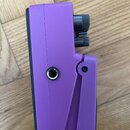 Fialový efekt pedál s černým spodním základem. Na boku jsou umístěny dva černé oválné ovládací knoflíky a jeden jack vstup/výstup. Povrch pedálu je m…