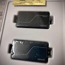 Dvě černé obdélníkové elektronické komponenty umístěné v bílém plastovém packagingu. Na každém kusu je v pravém dolním rohu bílý nápis FISHMAN. V hor…