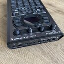 Černý sampler s mřížkou padů a ovládacími prvky. Na přední straně je bílý nápis SP-404MKII a logo Roland. Zařízení obsahuje několik otočných knoflíků…