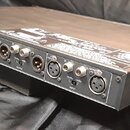 Zadní strana šedého rackového zařízení značky YAMAHA. Na panelu jsou umístěny konektory pro napájení, USB, WORD CLOCK, AES/EBU a několik výstupů OUTP…