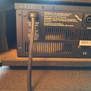 Zadní strana černého zesilovače s ventilací v dolní části. Je zde vidět napájecí kabel zapojený do vstupu MAIN INPUT 230V 50Hz a modrý konektor u náp…