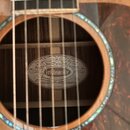 Detail akustické kytary s pohledem do ozvučovacího otvoru. Uvnitř je vidět štítek s nápisy CHICAGO, ORIGINAL, CELEBRATING 125 YEARS, WASHBURN, OF EXC…