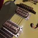Detailní pohled na tělo světle žluté kytary s dvěma f-otvory. Na tmavě šedém trsátoru je bílý nápis GRETSCH. Nástroj má dva stříbrné snímače s vidite…