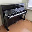 Černý digitální piano v şeklinde konzolového pianina s glossy povrchem. Na přihradě nad klávesnicí je bílý nápis "Pitmüller". Nástroj má standardní k…