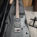 Černá elektrická kytara s výraznou strukturou dřeva na těle a hneděm hmatníkem. Nástroj má dva humbuckery, dva ovladače a stříbrný most s pružinami.…