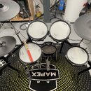 Elektronická bicí souprava značky Roland s černými rámy a bílými padovými plochami. Na padech a činelech je viditelné logo Roland. Souprava stojí na…