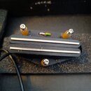 Černý elektrický snímač s dvěma stříbrnýmivýměnnými tyčemi (rail). Snímač je připevněn k černému plastovému podkladu a má připojení formou kabelu s b…