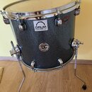 Tmavě šedý buben s kovovými obručemi a chromovaným stojanem. Na korpusu jsou vidět dvě nálepky, z nichž horní nese nápis DRUM CENTER.CZ a spodní kula…