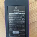 Zadní strana fialového efektpedálu s černým plastovým krytem. Na krytu je bílé logo a nápis behringer, text CONCEIVED AND DESIGNED BY BEHRINGER GERMA…