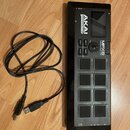 Černý sampler s osmi gumovými pady a displejem. Na přístroji jsou nápisy AKAI professional, MPX8 MOBILE SAMPLE PLAYER a označení 3D. K zařízení je př…