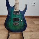 Elektrická kytara s modro-zeleným přechodovým barevným lakem a viditnou strukturou dřeva. Nástroj má tři humbuckery, jeden ovládací knoflík a přepína…