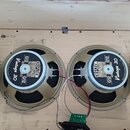 Dva reproduktory značky CELESTION s nápisy LOUDSPEAKERS, G12 a Vintage 30. Reproduktory mají béžové rámy a jsou umístěny v dřevěné bedně. Mezi nimi j…