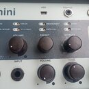 Detailní pohled na ovládací panel komba s nápisem mini. Horní část obsahuje konektory USB, PHONES a AUX, přepínače s označením NATURAL, PARLOR, DREAD…