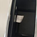 Detailní pohled na černý povrch přístroje s přilepeným bílým papírovým štítkem. Na štítku je černý text MODEL:LAVA ME a níže CMIIT:2023AP5094. Štítek…