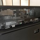 Zadní strana černého kytarového komba s mřížkou, za kterou jsou vidět vnitřní komponenty. Na spodním černém panelu je bílý nápis Laney v zeleném ovál…