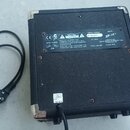Zadní strana černého kytarového komba s texturovaným povrchem a kovovými rohy. Na černém štítku jsou nápisy: CE, CAUTION, SERIAL NUMBER AX 0658883, M…