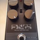 Černý efekt pedál s nápisy tc electronic a FANGS METAL DISTORTION. Na horní straně jsou čtyři černé ovládací knoflíky a červená kontrolka. Uprostřed…