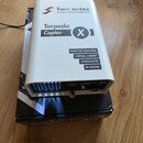 Bíle provedené zařízení s kovovým šasi a černými nápisy. Na horní části je logo a text Two notes AUDIO ENGINEERING, dále označení Torpedo Captor X a…