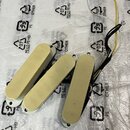 Tři elektrické snímače pro kytaru v krémové barvě. Snímače mají obdélníkový tvar se zaoblenými konci a jsou vybaveny připojovacími kabely v černé, žl…