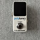 Bílý kompaktní kytarový ladič s černým displejem. Na přední straně jsou nápisy „polytune2 mini“, „true bypass“ a logo „tc electronic“. Zařízení vykaz…