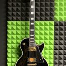 Černá elektrická kytara s tmelem hmatníkem a bílými blokovými vložkami. Na hlavě je bílé logo Epiphone a symbol v podobě kosočtverce. Tělo je lesklé,…