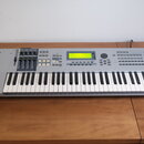 Stříbrný digitální klavír s klávesnicí. Na levé straně je logo YAMAHA a vpravo nápis MOTIF ES6. Nástroj má centrální displej, několik posuvníků a sad…