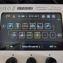 Detailní pohled na displej a horní část bílého efektového procesoru. Na šasi je nápis AMPERO II STAGE, CDCM HD Gen 2, Tri-Core DSP a Amp Modeler / Ef…