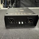 Černý kovový box s dvěma XLR konektory na přední straně a dvěma bílými přepínači mezi nimi. Na horní části jsou nápisy BALANCED OUTPUT, LIFT a GND u…