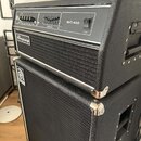 Černý basový zesilovač a reproduktorová skříň s texturovaným povrchem. Na horním panelu zesilovače je nápis SVT-450, přepínač Power a logo Ampeg. Pře…