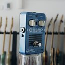 Modrý efekt pedál s nápisem MULTICOMP a podtitulem True Dual Band Compressor. Na horní části jsou dva bílé ovládací knoflíky s popisky COMP/LIMIT a G…